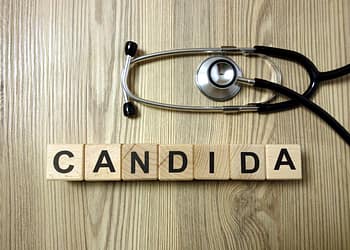 Wooden blocks with the word 'CANDIDA' arranged on a wooden surface, with a stethoscope placed partially on top of them.
