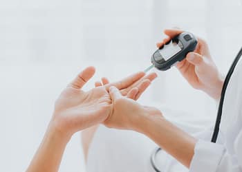 A healthcare professional is measuring a patient's blood glucose level using a glucose meter.