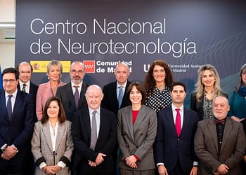 Groups of people posing in front of a background with the text "National Center for Neurotechnology", in a professional environment.