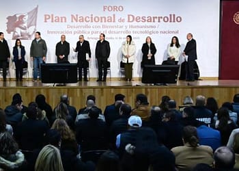 A group of people standing on a stage during a forum titled "National Development Plan", with an audience sitting in front of them.