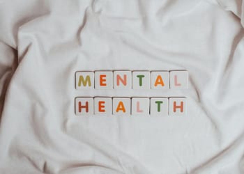 Colorful letters spelling out the words "MENTAL HEALTH" on a white fabric background.