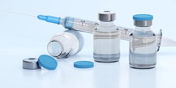 Clear medicine vials with blue caps and a syringe on a light background, some vials are tilted while others are upright.