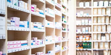 Shelves in a pharmacy with various products in boxes, including medications and personal care products.