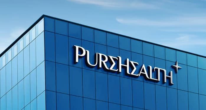 Blue glass facade building with "PUREHEALTH" sign in white letters, against a clear sky background.