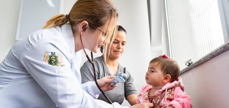 A doctor examining a little girl while a woman accompanies her.