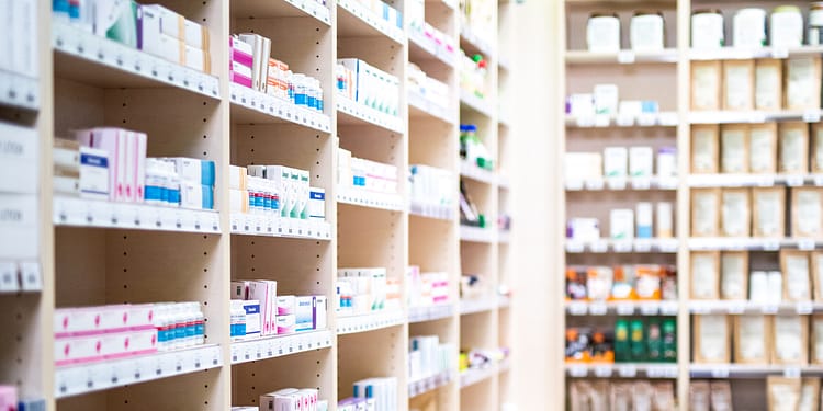 Shelves in a pharmacy with various products in boxes, including medications and personal care products.