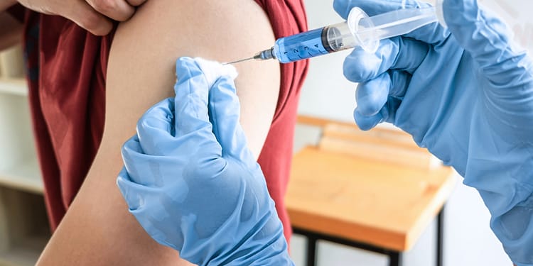 Person receiving an injection in the arm, with one hand holding the syringe and the other holding the upper arm.
