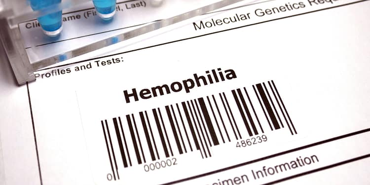 Label on a genetic application form showing the word "Hemophilia" and a barcode, with test tubes in the background.