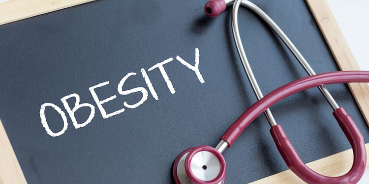 A red stethoscope on a black board with the word "OBESITY" written in white letters.