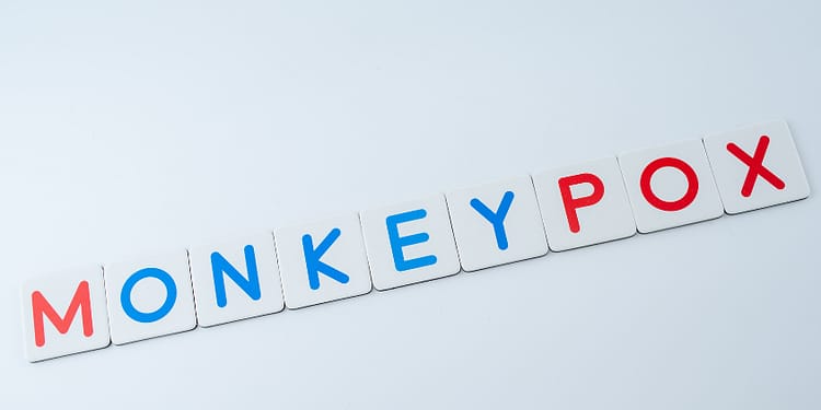 Wooden letters that spell out the word "MONKEY POX" in blue and red on a white background.