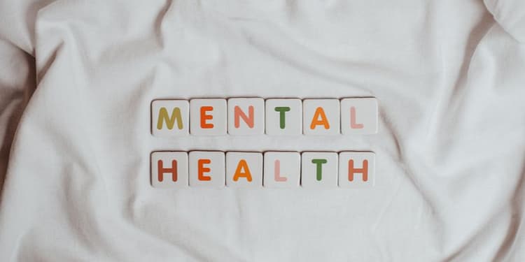 Colorful letters spelling out the words "MENTAL HEALTH" on a white fabric background.