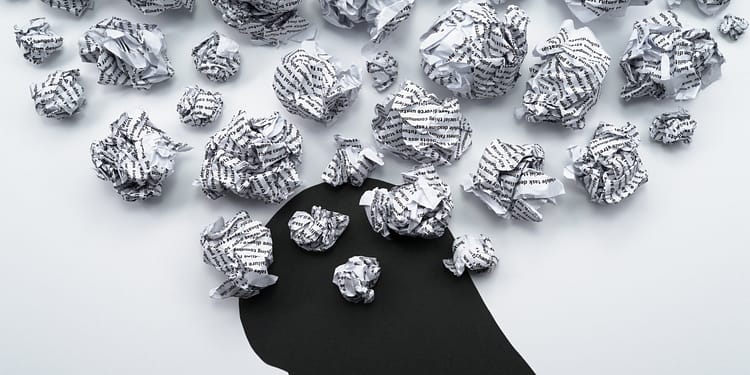 Black silhouette of a head with crumpled paper scattered around, symbolizing discarded ideas or thoughts.