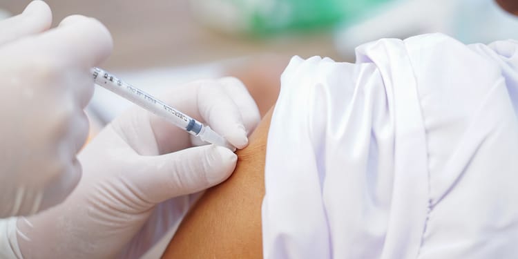 Inyección administrada a brazo desnudo por una mano con guante.